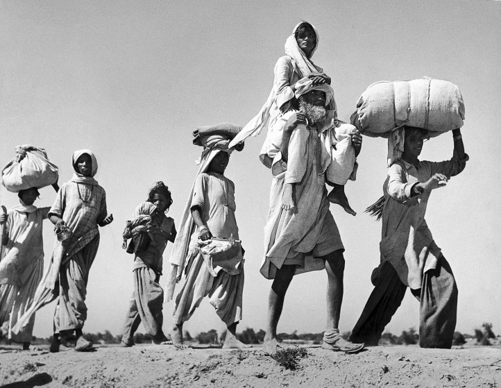 Sikh carrying his wife on his shoulders as he walks with others migrating to their new homeland after the creation of Sikh and Hindu section of Punjab India due to the division of India.